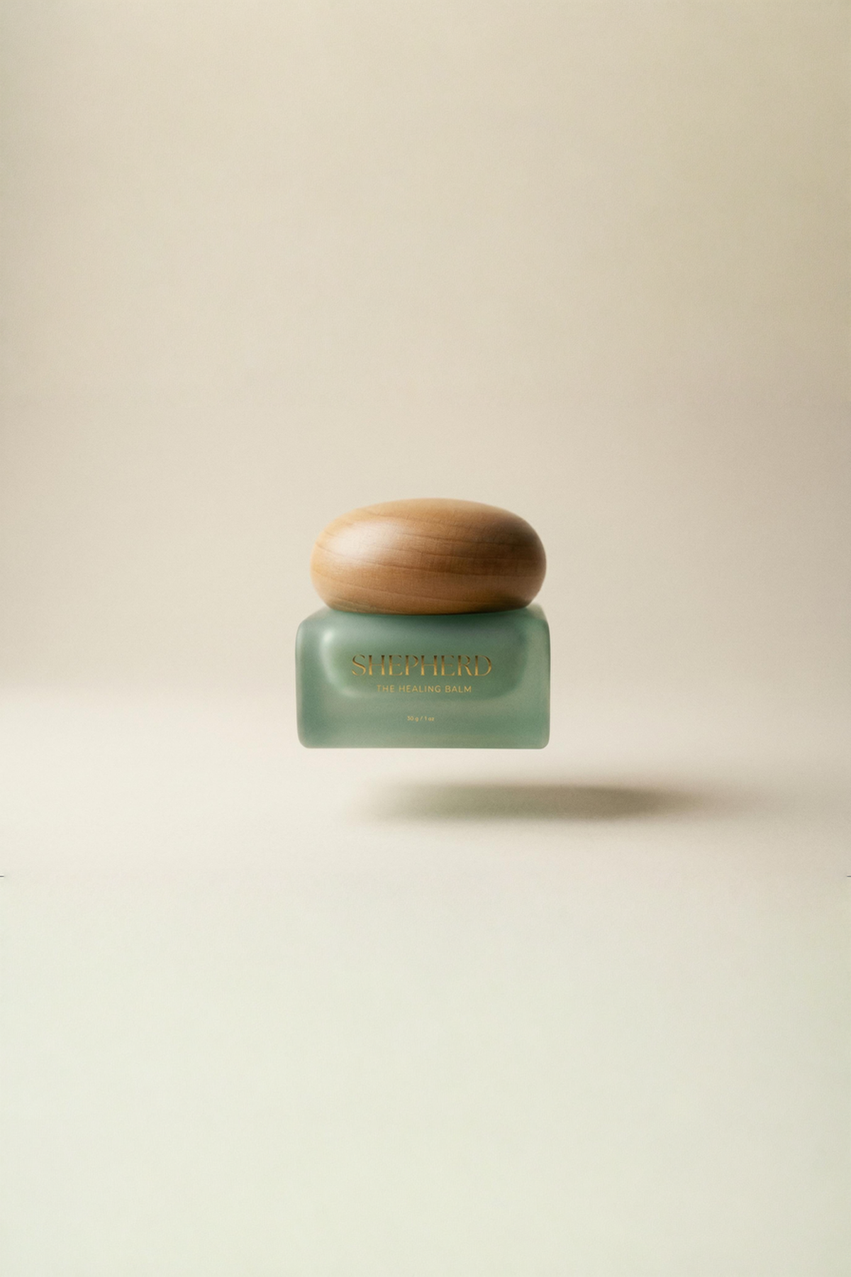 The Healing balm: Green jar with golden text that reads: SHEPHERD, THE HEALING BALM. With wooden circular lid on an ivory beige background.